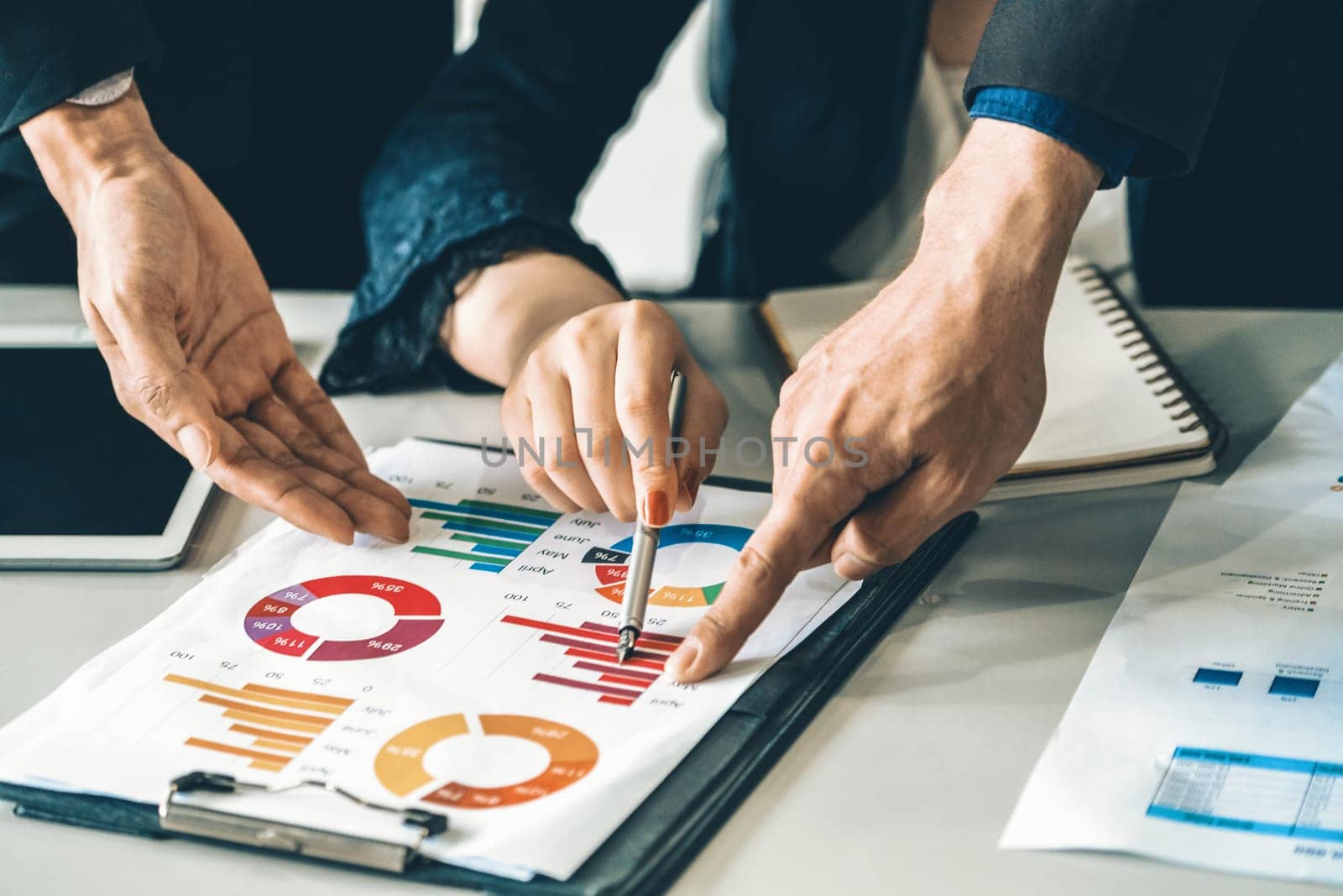 Businessman and businesswoman in meeting working with many financial statement document on desk. Concept of busy business profit analysis and brainstorm. Close up shot at people hands and papers. uds