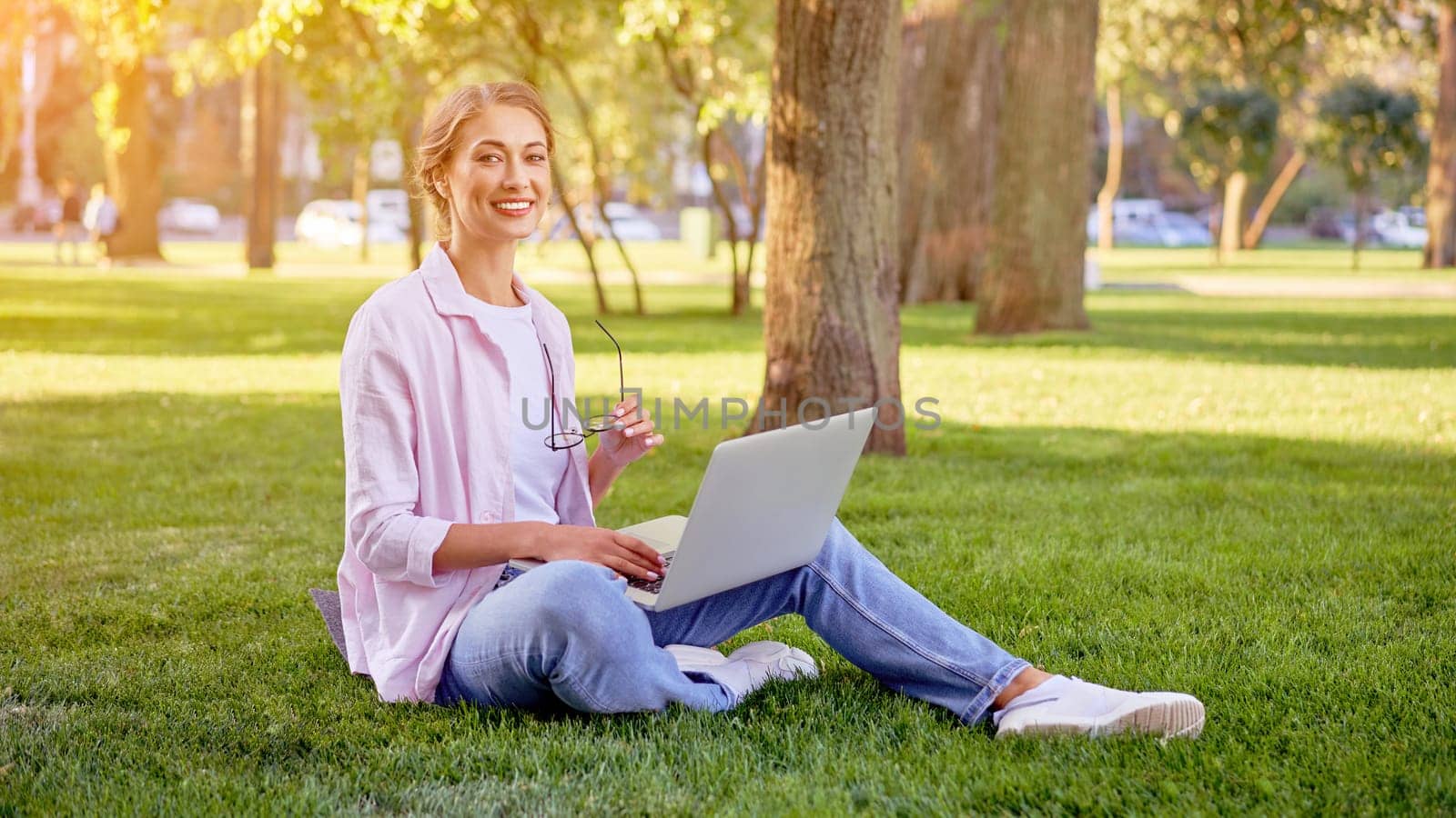 Businesswoman sitting grass summer park using laptop Business person working remote. Outdoor Successful european caucasian woman freelancer make video call teacher study work online lessons