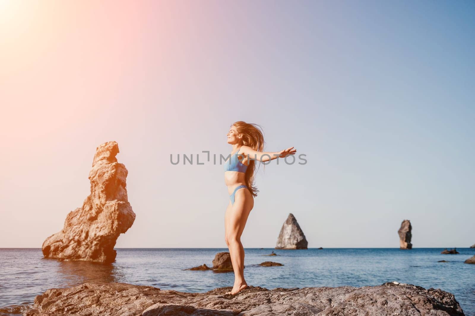 Middle aged well looking woman with black hair doing Pilates with the ring on the yoga mat near the sea on the pebble beach. Female fitness yoga concept. Healthy lifestyle, harmony and meditation.