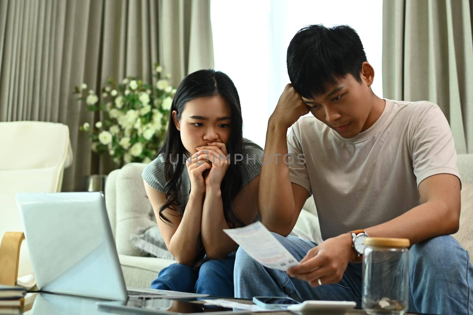 Unhappy young couple calculating family spends together and feeling depressed