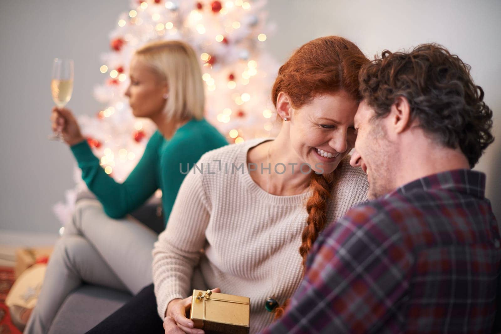 Christmas, gift and couple embrace with love for holiday in home, smile and happiness. Marriage, woman and man as husband and wife in house for celebration of festive, season and romance on vacation.