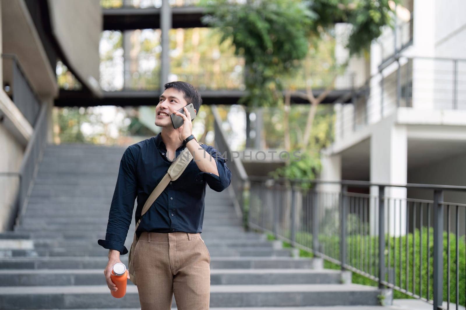 Smiling asian businessman walking to work while to hold reusable eco friendly ecological cup in the city.