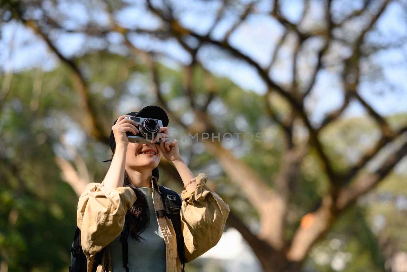 Female tourist taking pictures with vintage camera in the forest and enjoying beautiful nature.