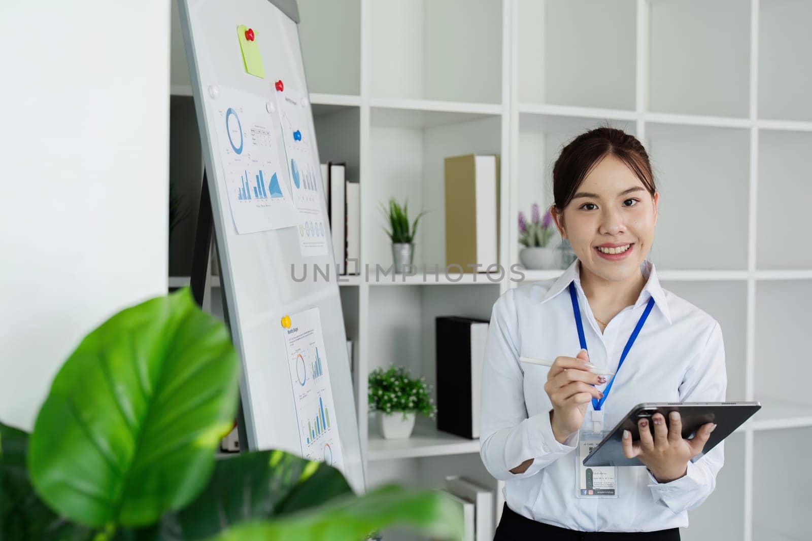 woman standing in front of whiteboard with tablet for present Profit analysis of company while meeting.