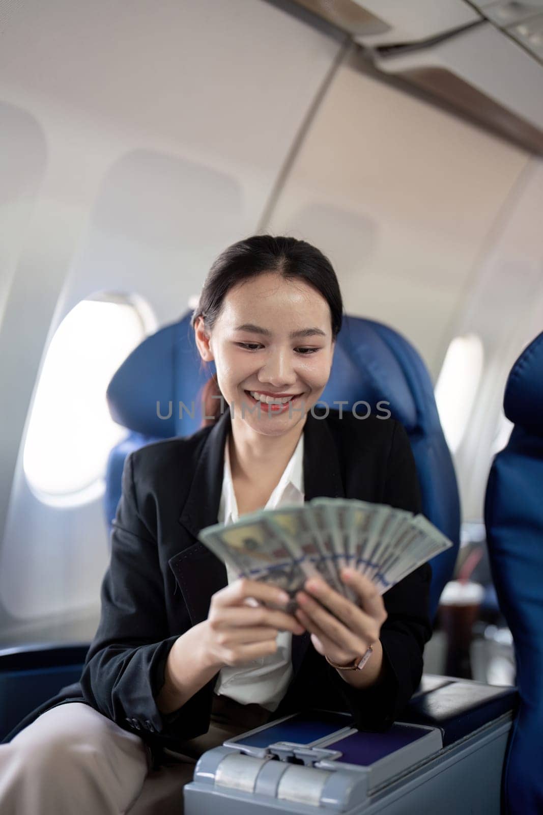 Young business woman successful with money in hand and on sit airplane by nateemee