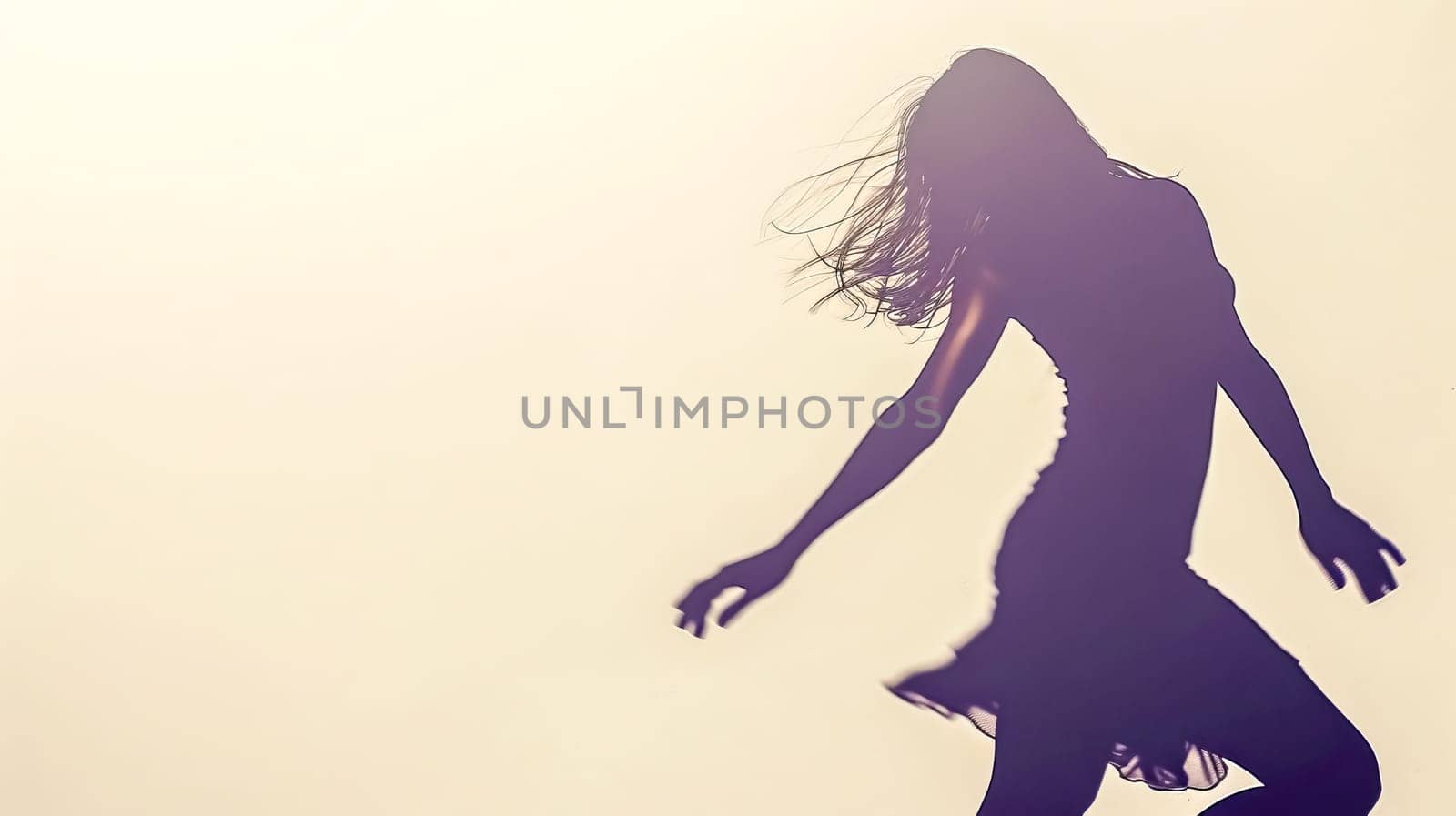 Backlit silhouette image capturing the carefree dance of a woman against a soft sunset glow
