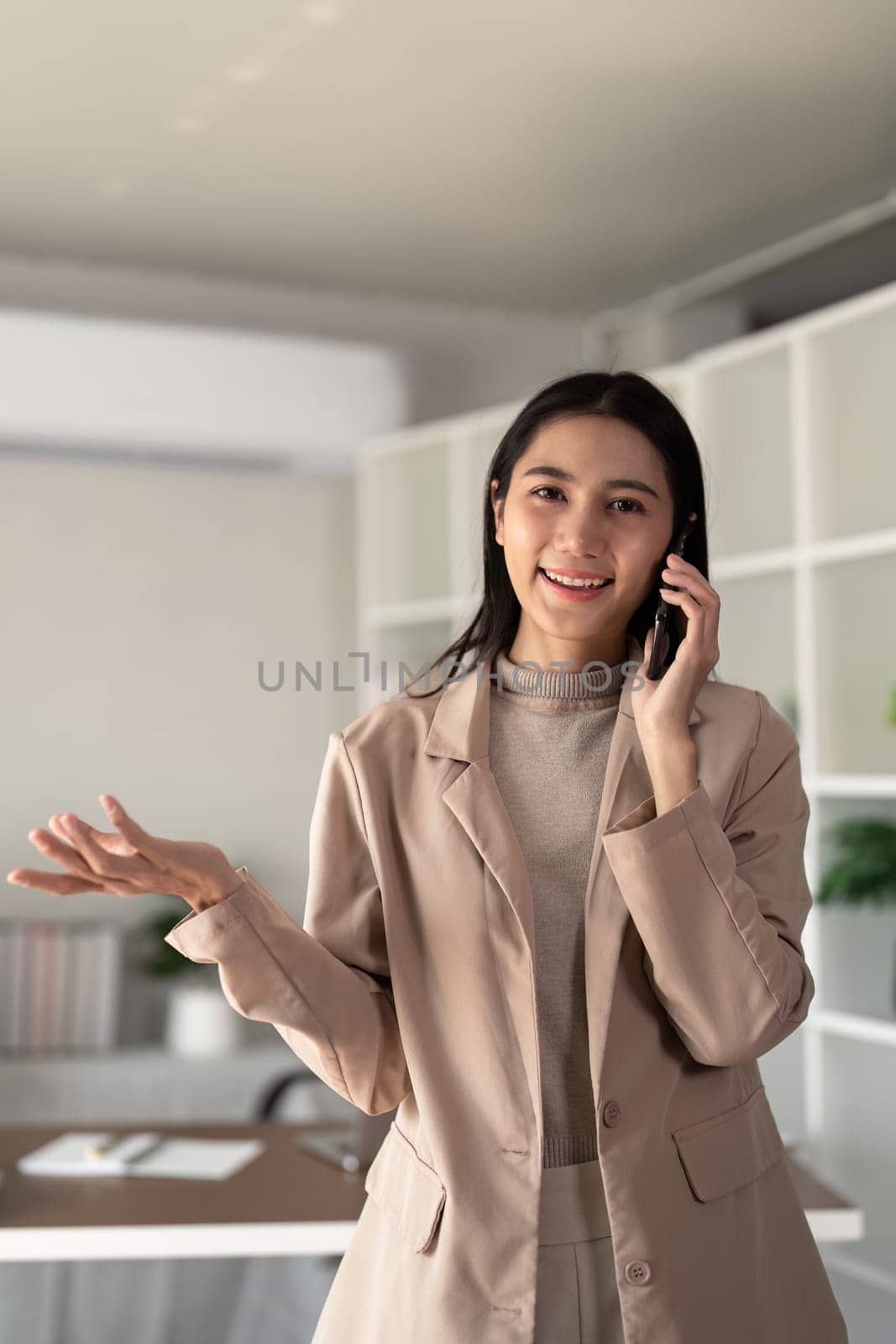 Young business woman asian talking on mobile phone while working with laptop at desk home.