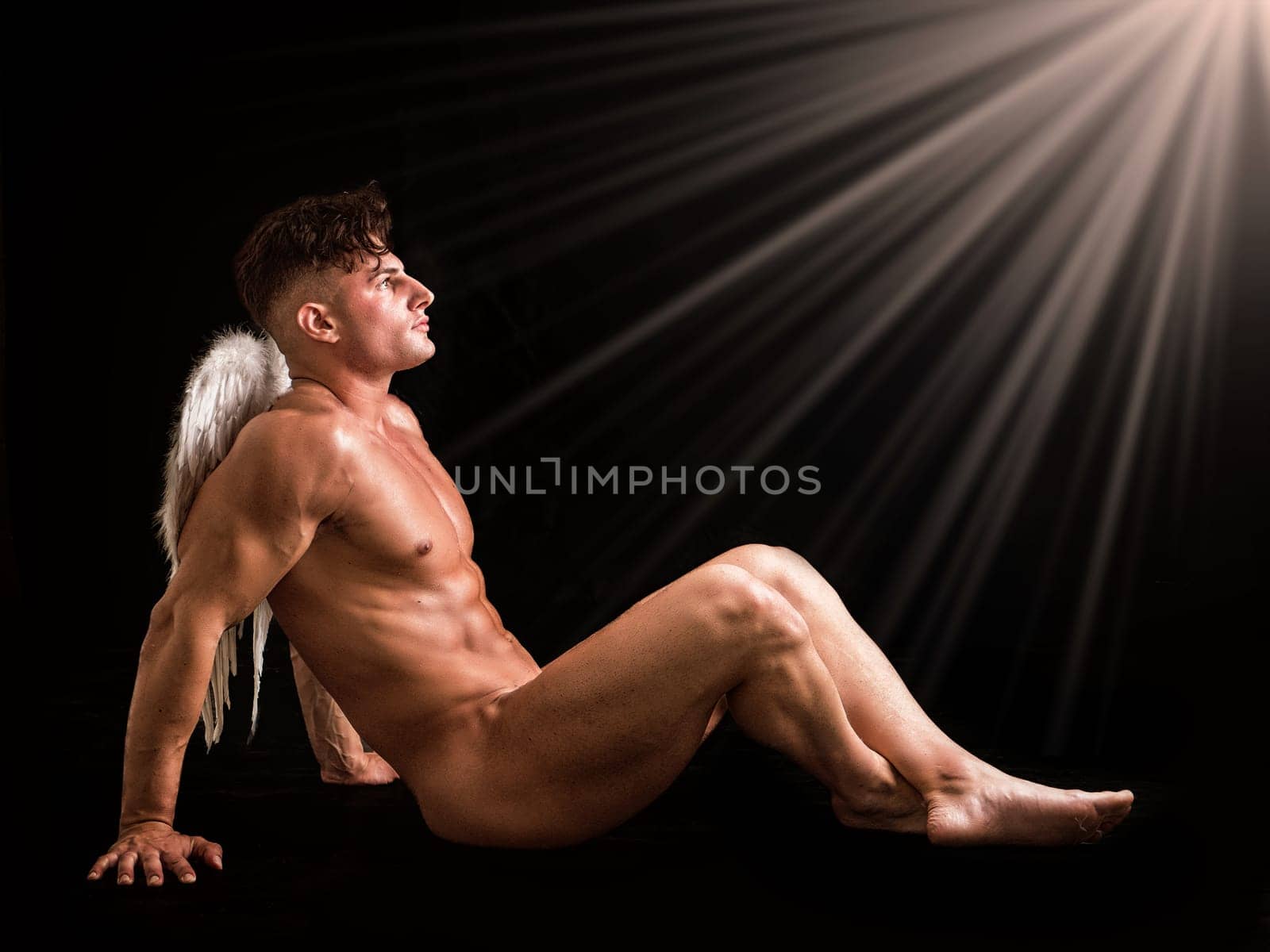 Naked man with angel wings sitting on the ground by artofphoto