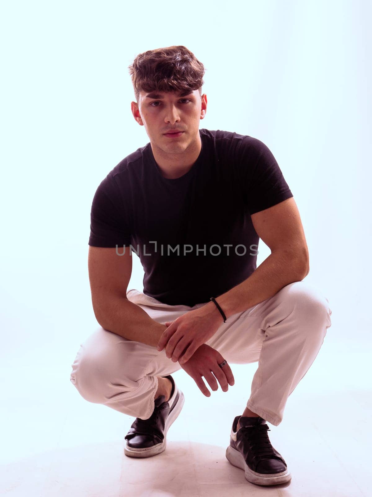 Man kneeling down in black shirt and white pants by artofphoto