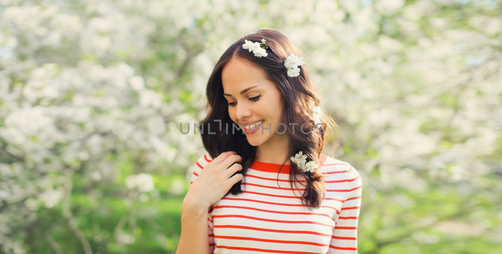 Portrait of lovely happy smiling young woman in spring blooming garden with white flowers on the trees in park