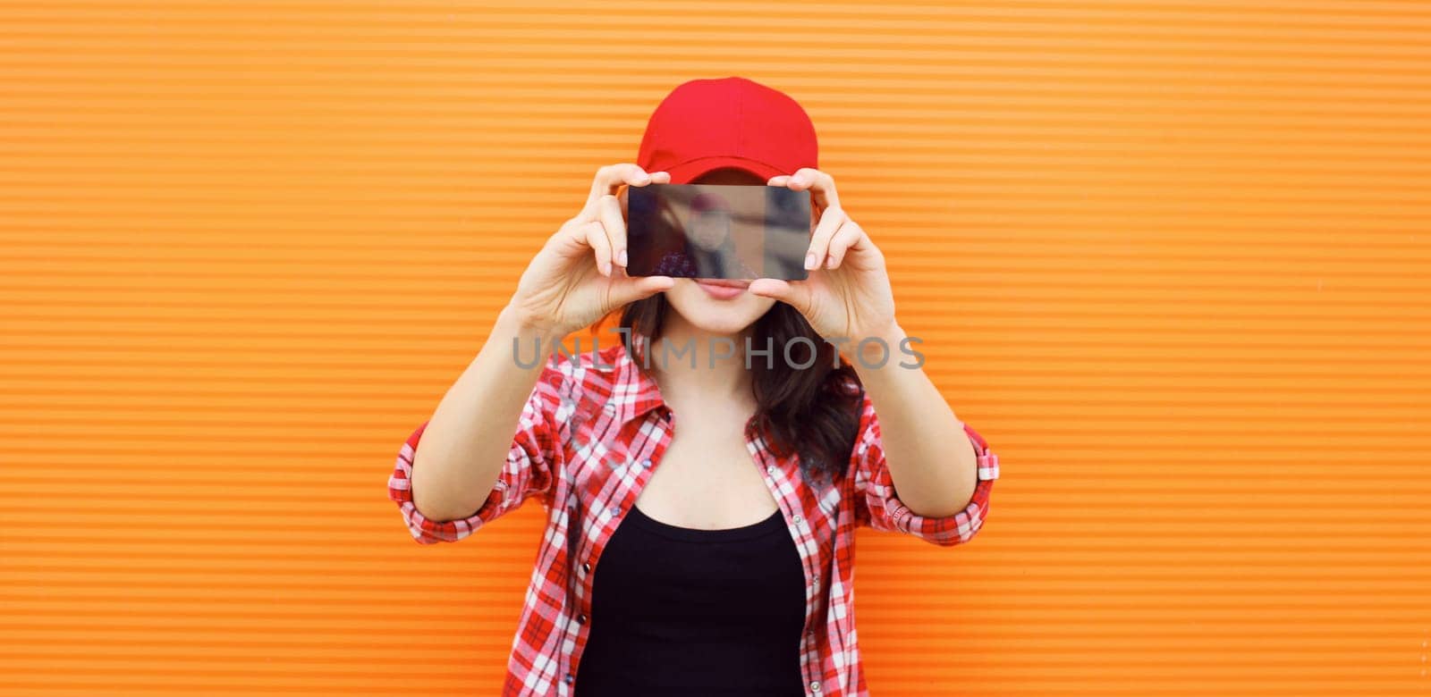 happy young woman taking selfie with mobile phone on colorful orange background by Rohappy