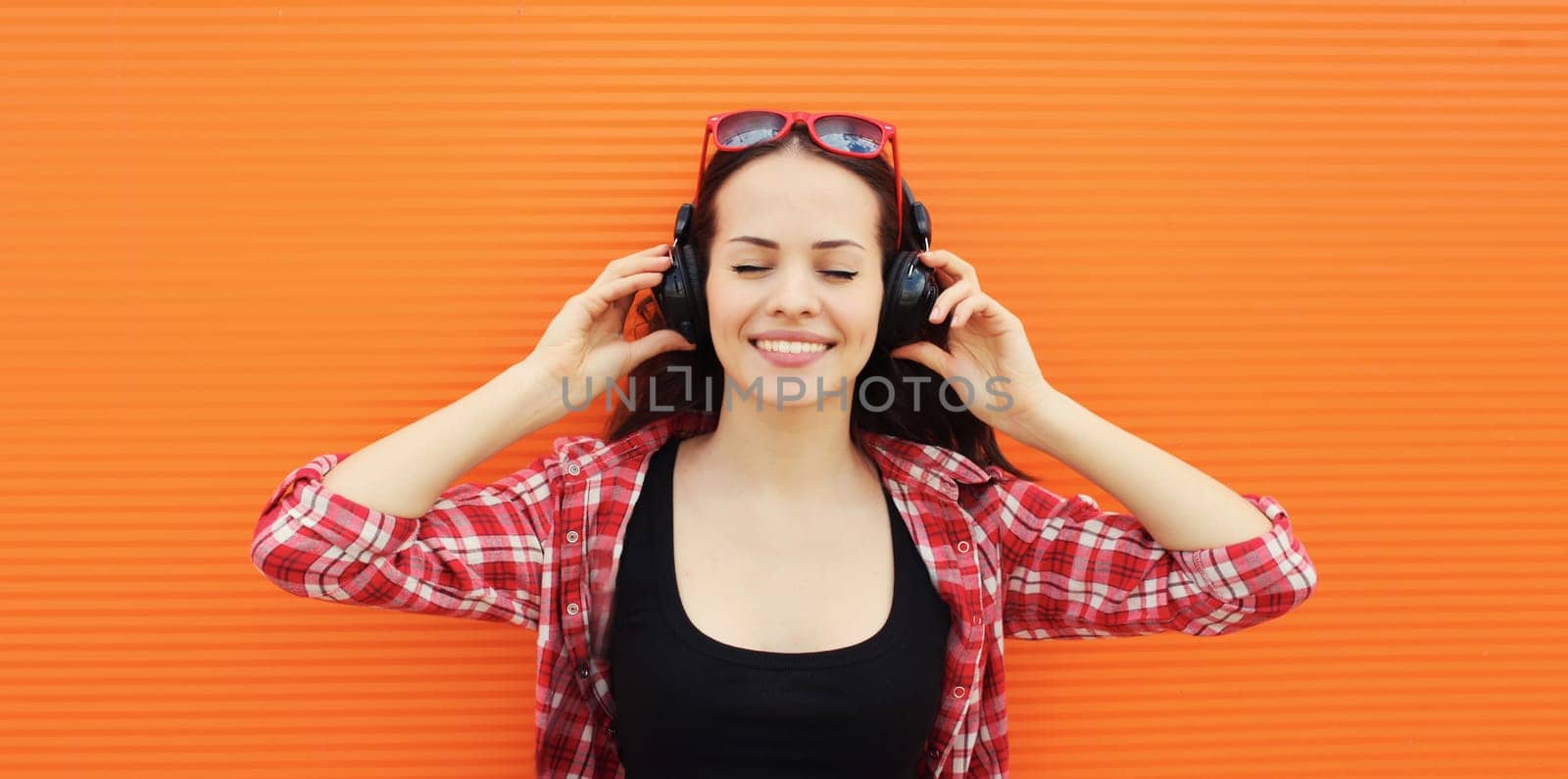 Summer portrait of happy smiling young woman listening to music in headphones by Rohappy