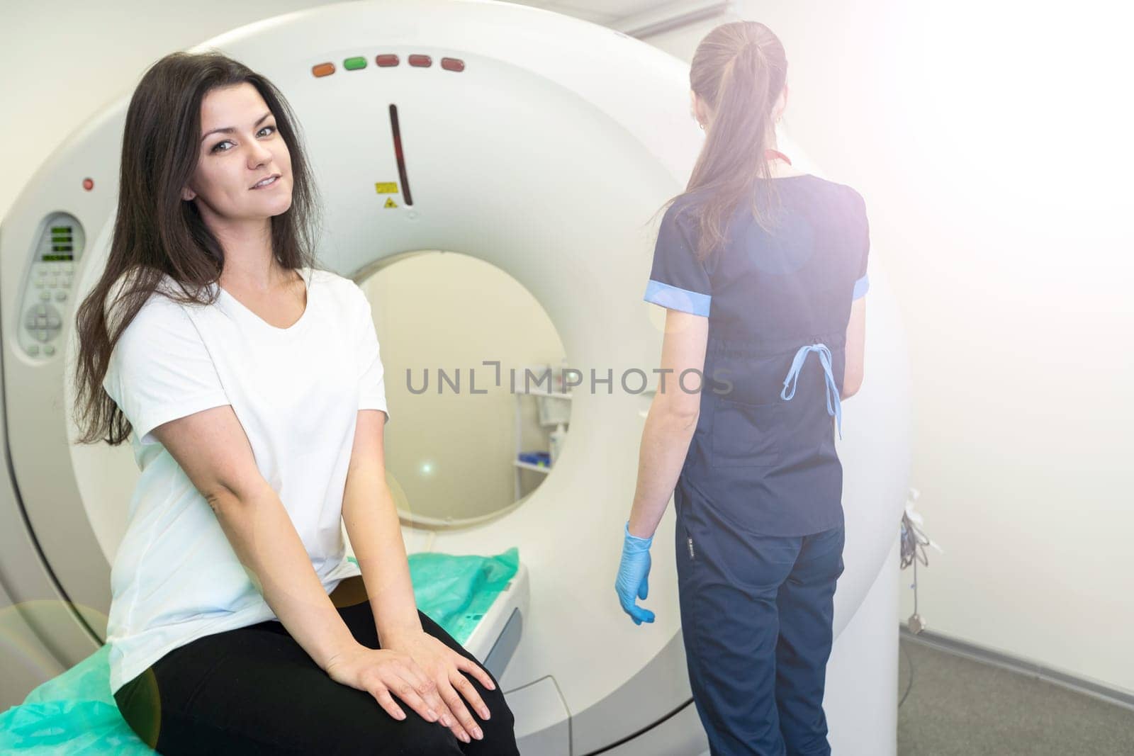 CT scan technologist overlooking patient in Computed Tomography scanner during preparation for procedure. Woman patient going into CT scanner. by Andelov13
