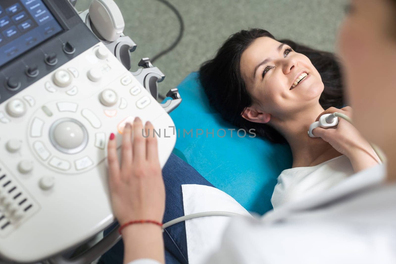 Doctor using ultrasound scanning machine for examining a thyroid of woman