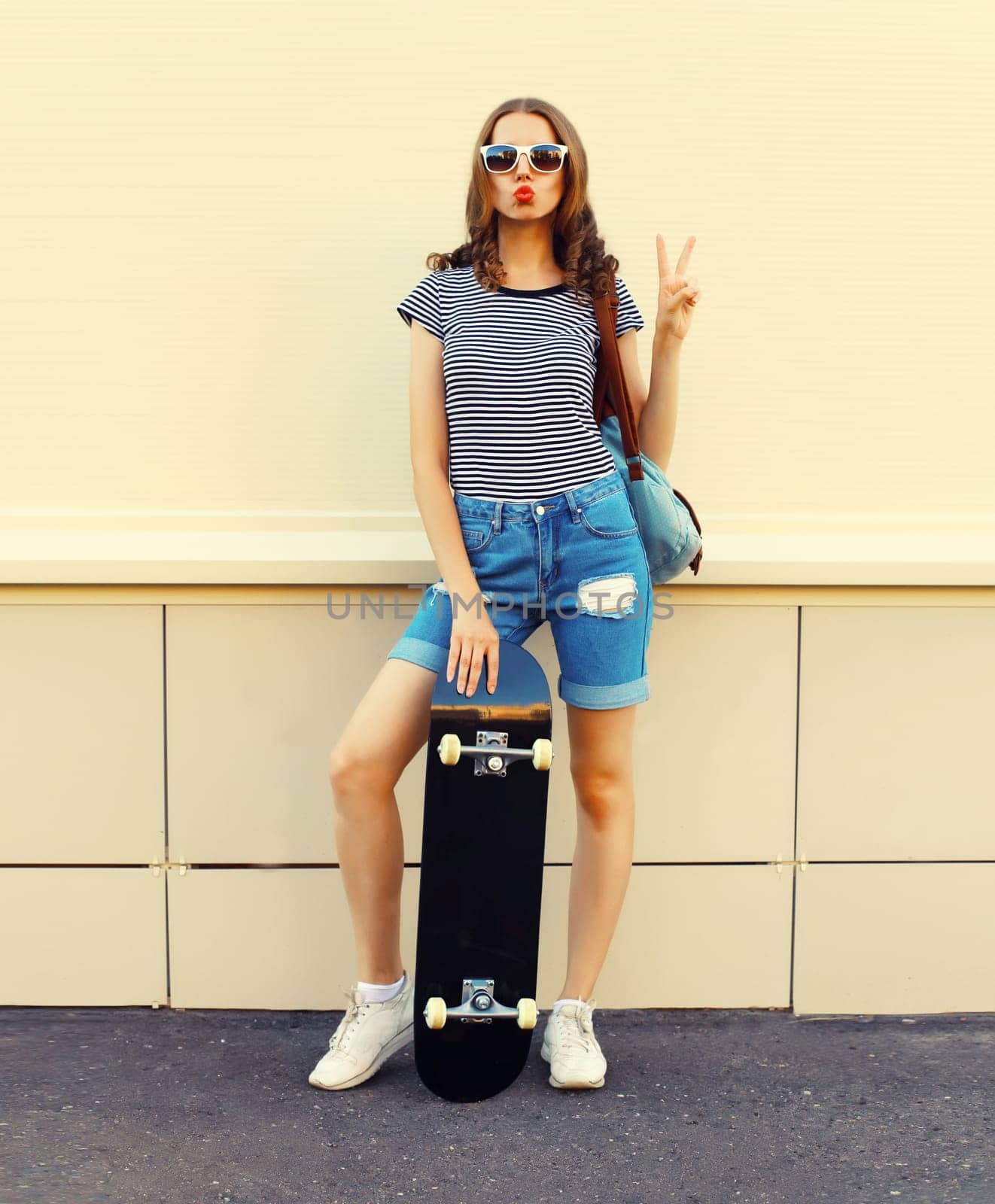 Portrait of cheerful young woman with skateboard in the city by Rohappy