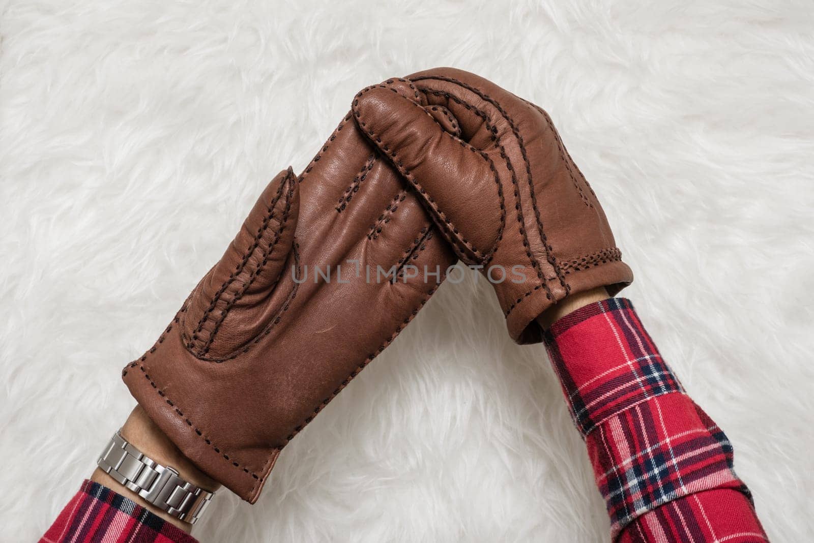 closeup men's hand taking off the brown leather gloves over white fur.