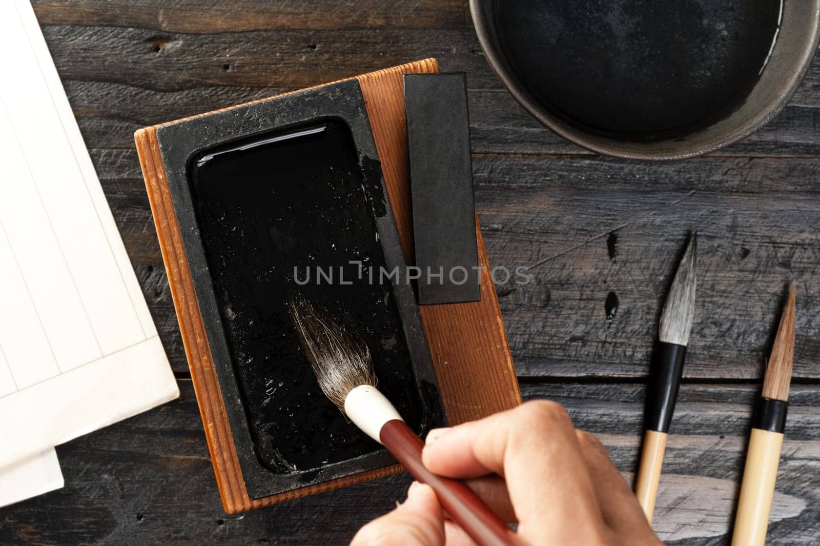 inkstone and brush, closeup man's hand using brush and traditional inkstone