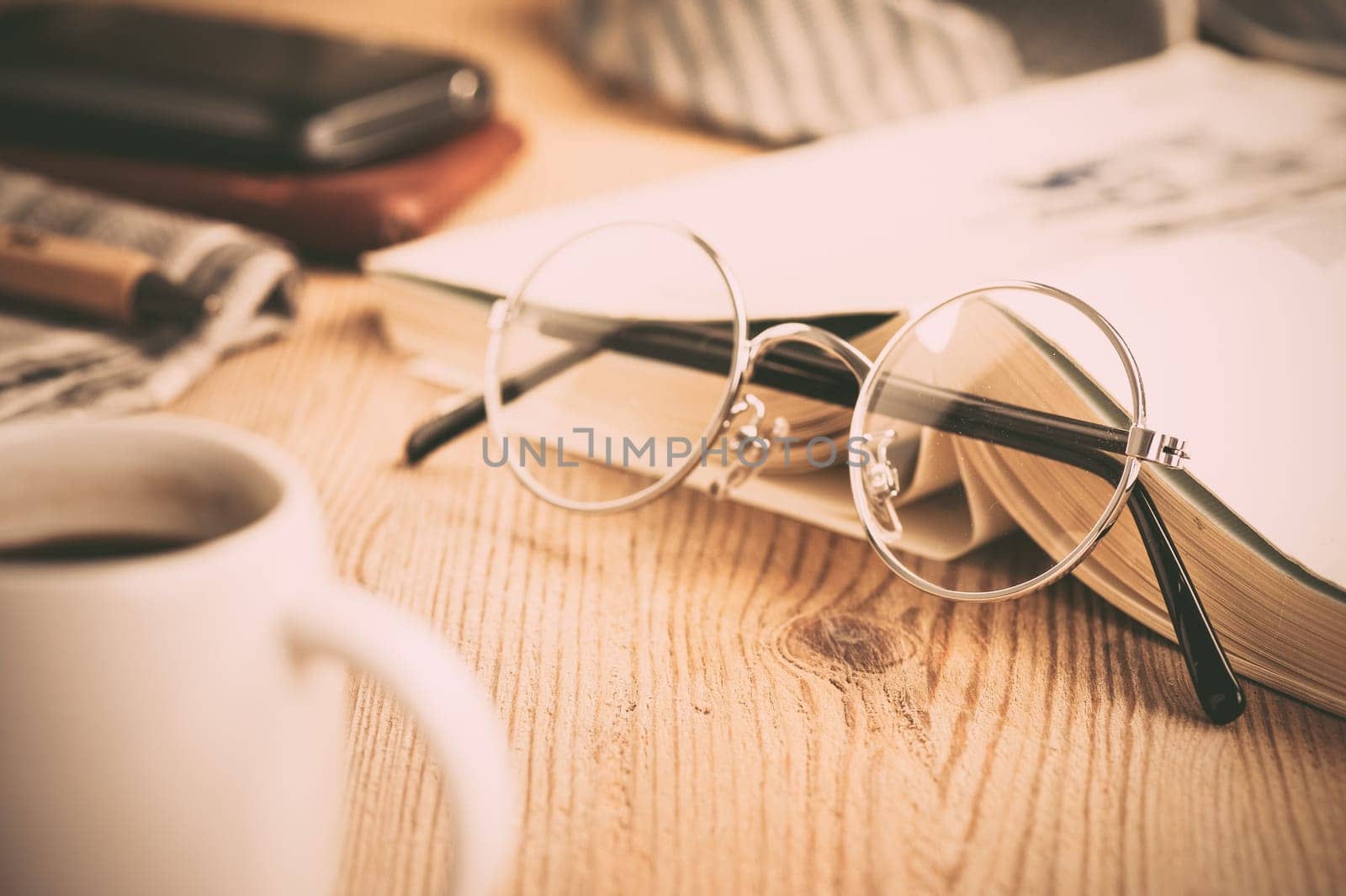closeup round frame style of eyeglasses on wooden desk, shallow depth of field and filtered