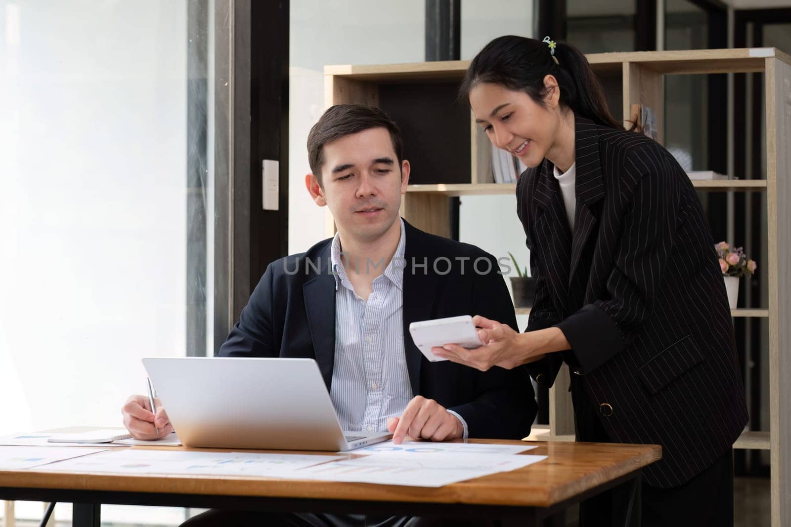 Two businessmen discussing project at the office room Businessman discusses project planning with colleagues in modern workplace while having discussion and advice on financial data report. by wichayada