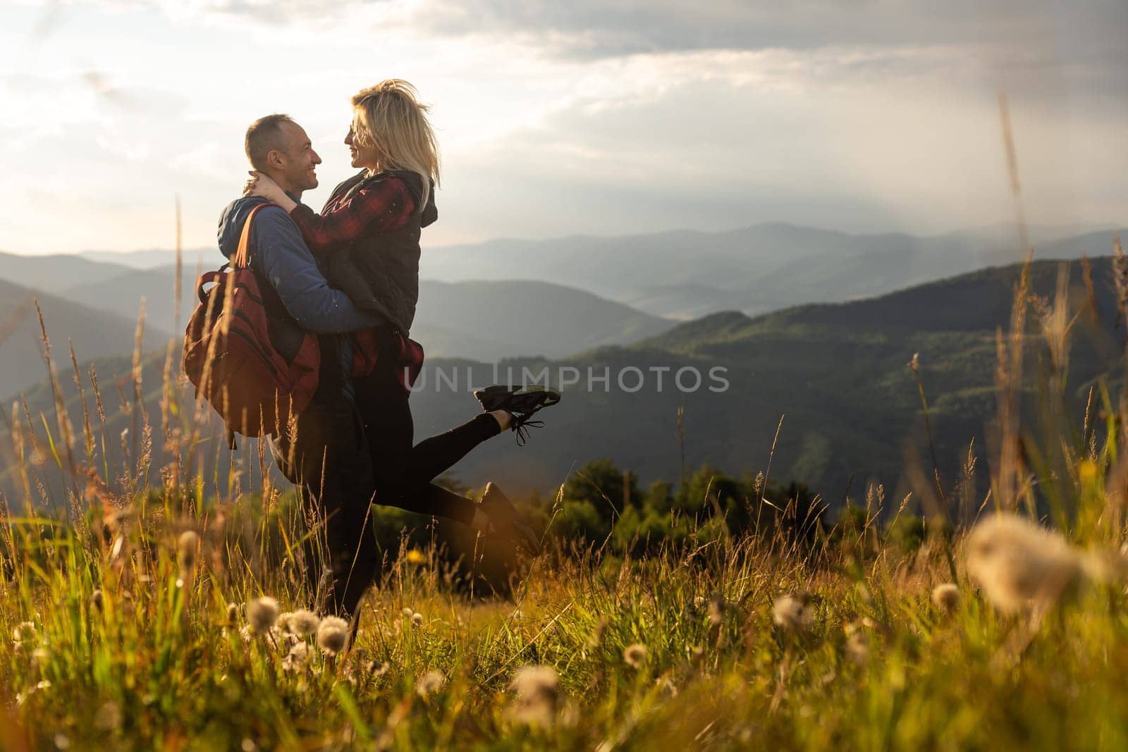 Man and woman standing and hugging on the top of the mountain, autumn hike with backpacks.