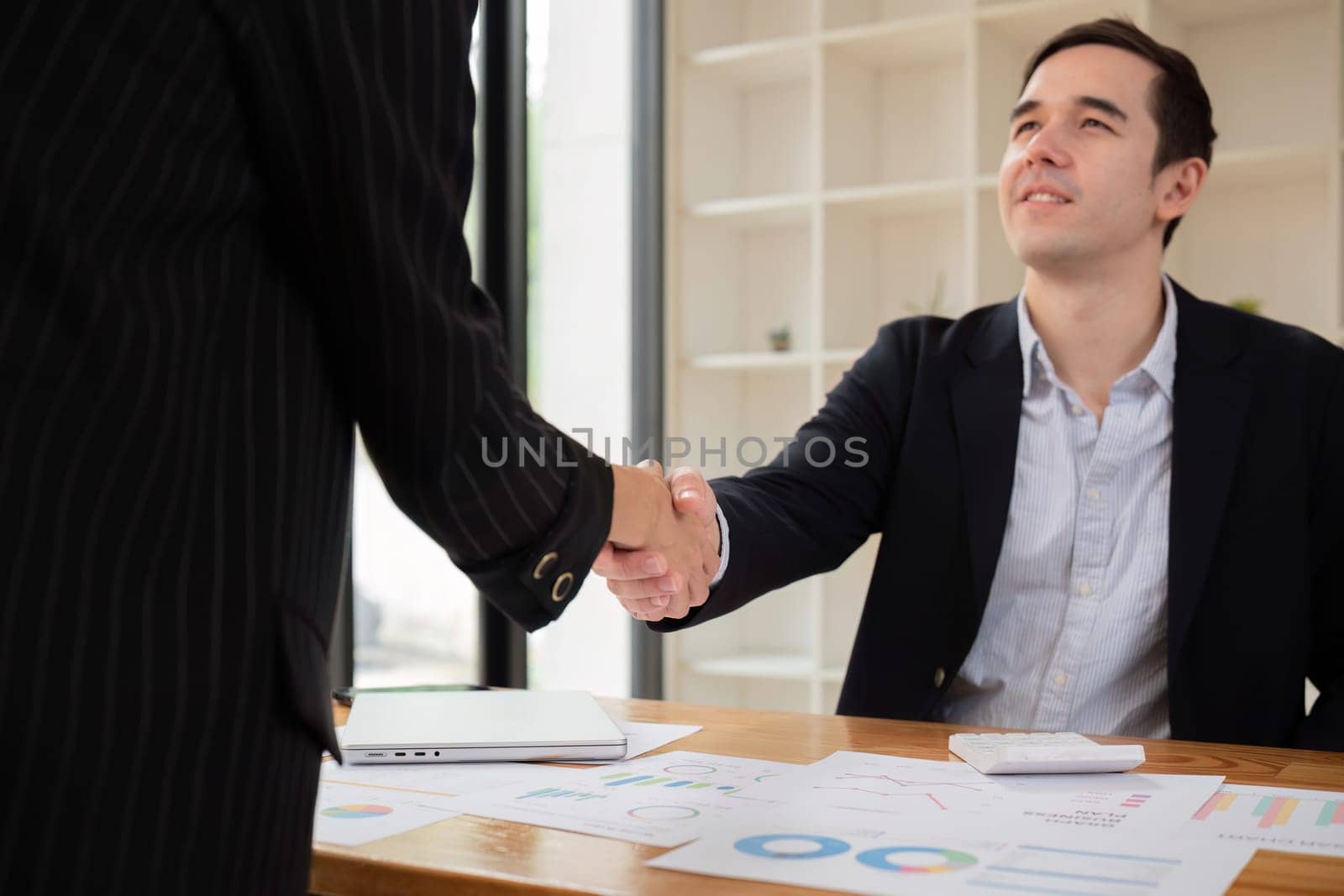 Businessmen shake hands after a meeting, congratulating colleagues and reaching a business agreement. by wichayada