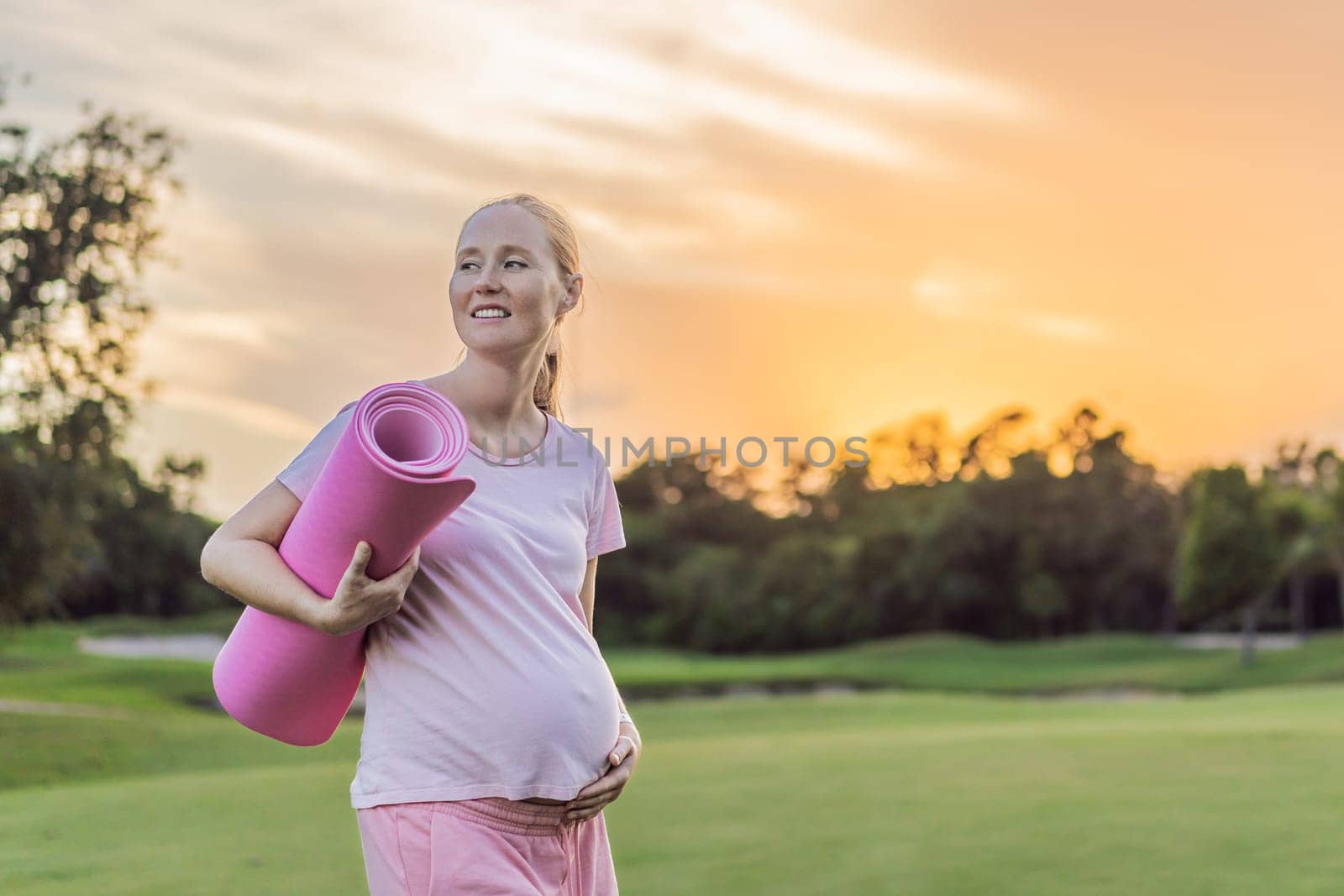 Energetic pregnant woman takes her workout outdoors, using an exercise mat for a refreshing and health-conscious outdoor exercise session by galitskaya