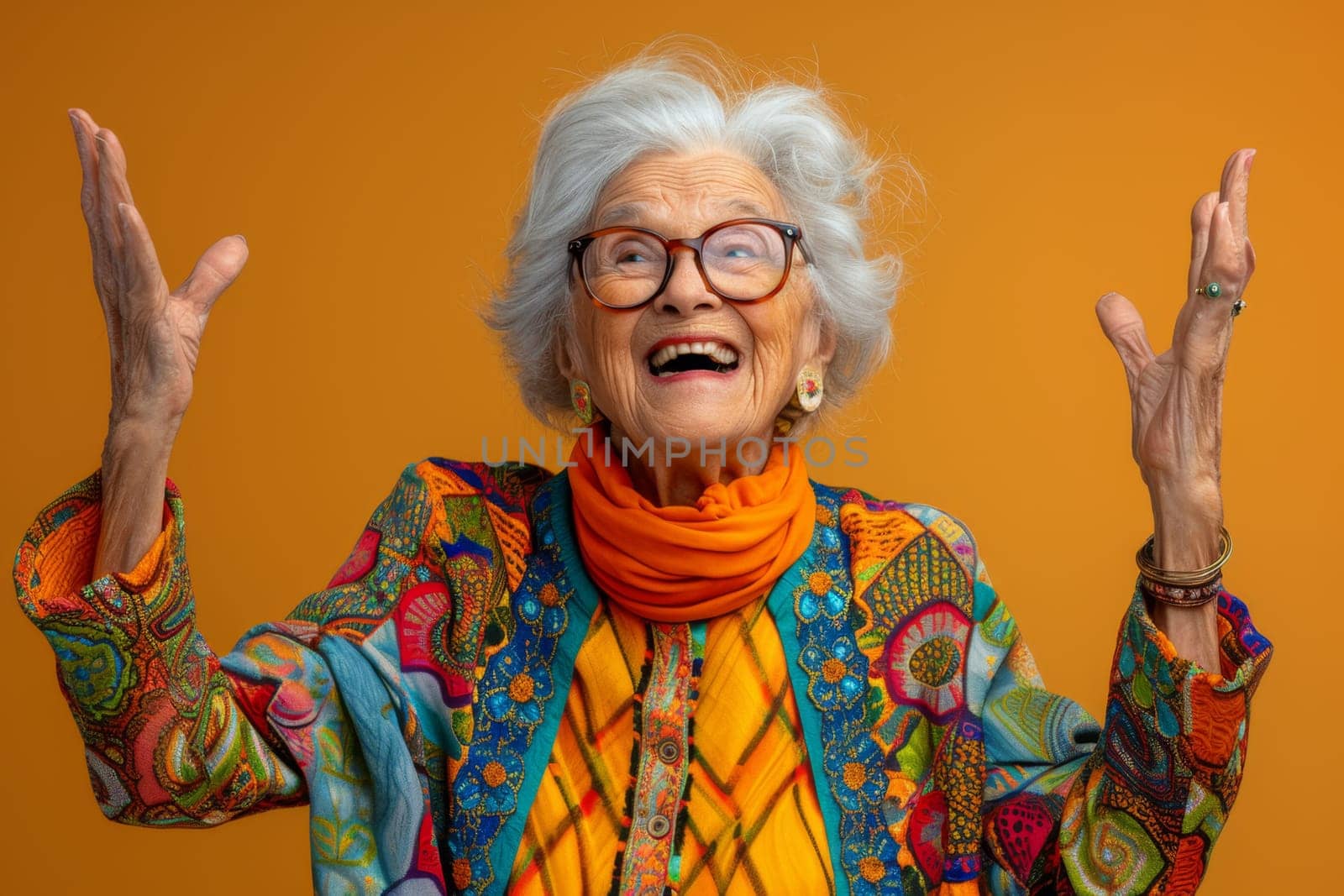 A happy and playful elderly woman in colored clothes on a yellow background.