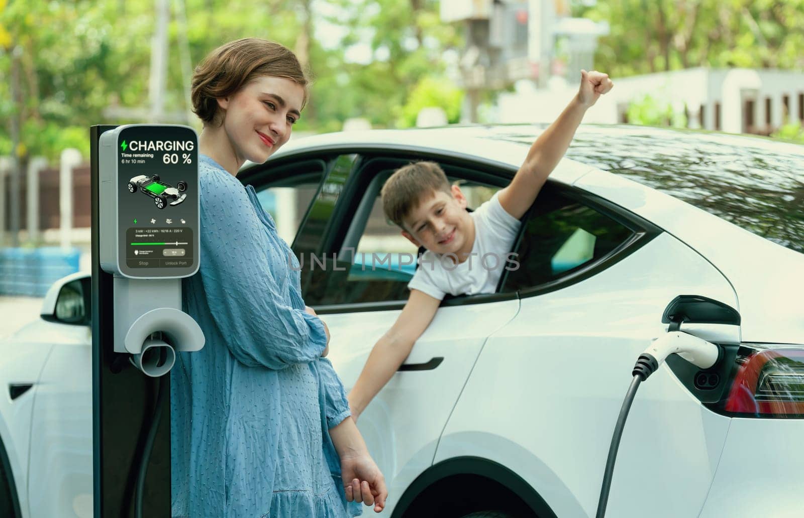 Environmental awareness family with eco-friendly electric car recharging battery from home EV charging station with little boy inside the car. Rechargeable and EV car technology. Perpetual