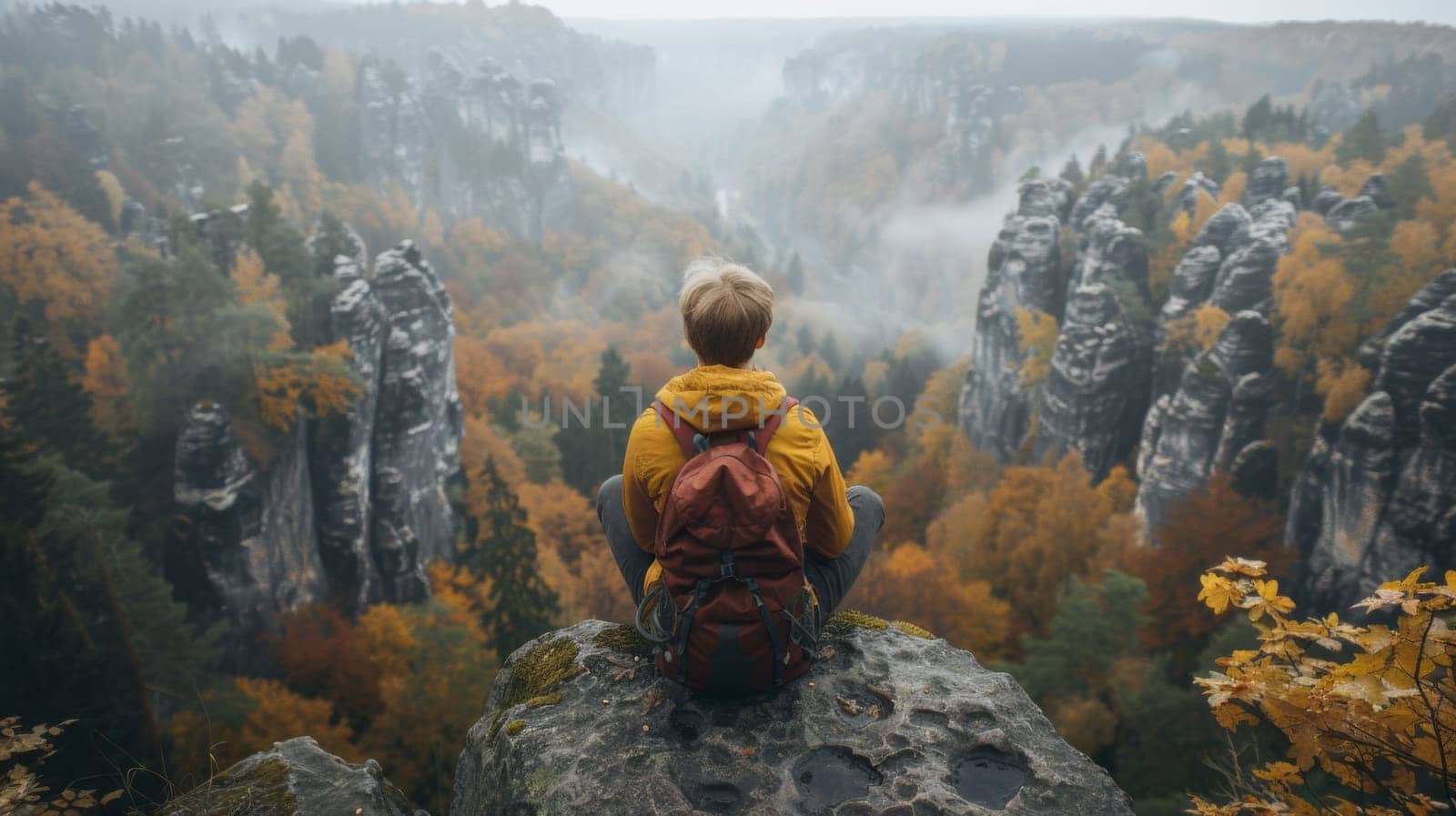 A person sitting on a rock with backpack looking at the mountains