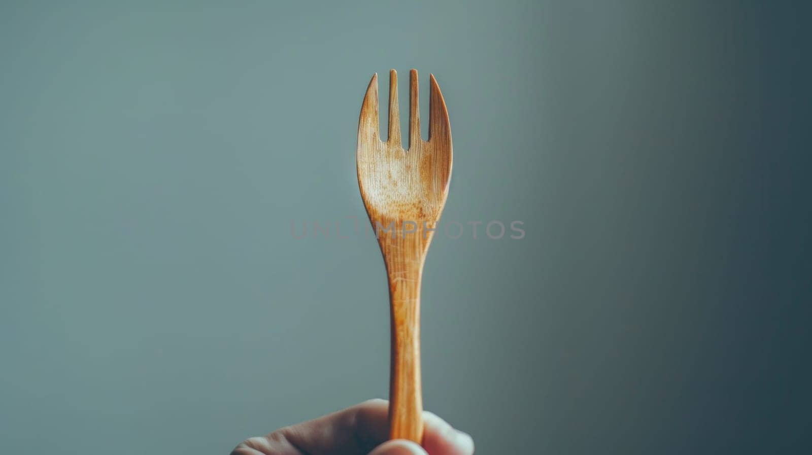 A person holding a wooden fork in their hand