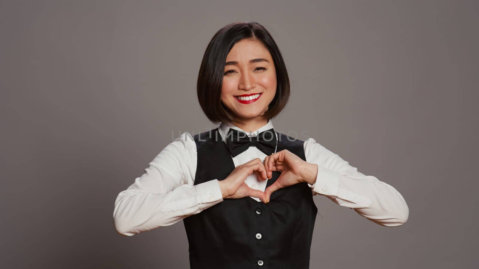 Hotel administrator shows heart shape symbol on camera by DCStudio