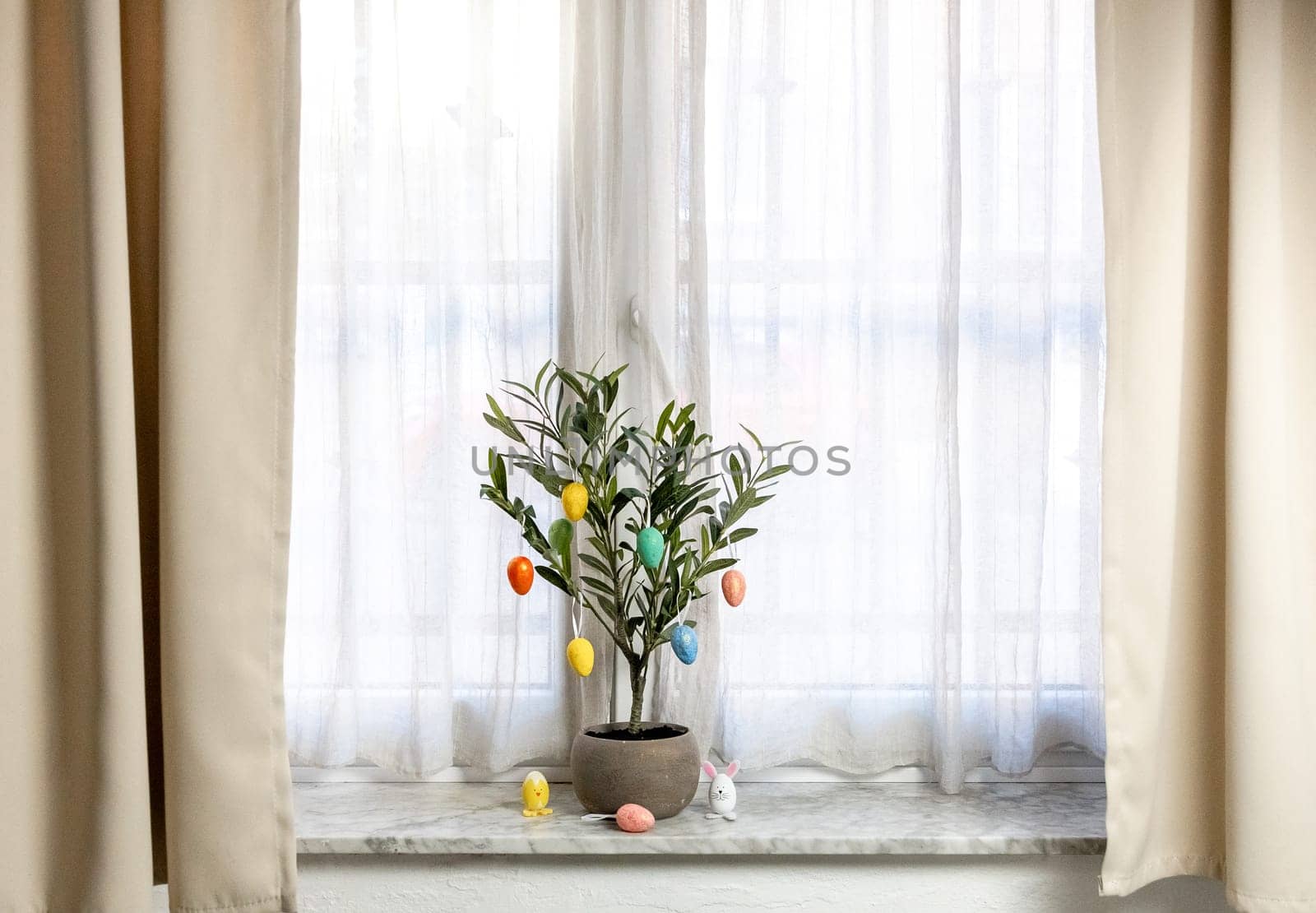 Easter eggs on green tree branches on the windowsill. by Nataliya