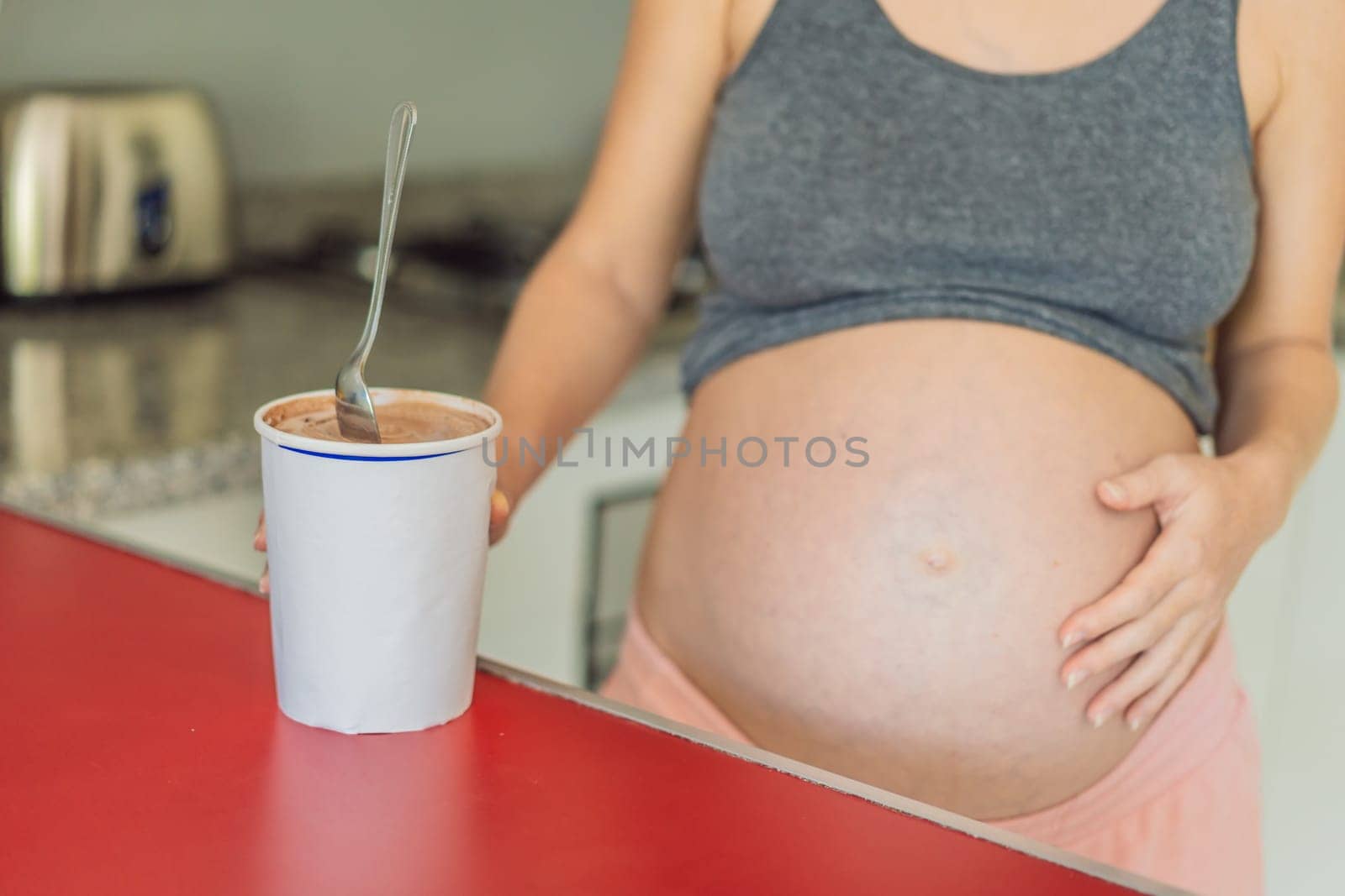 Happy pregnant young woman eating ice cream.