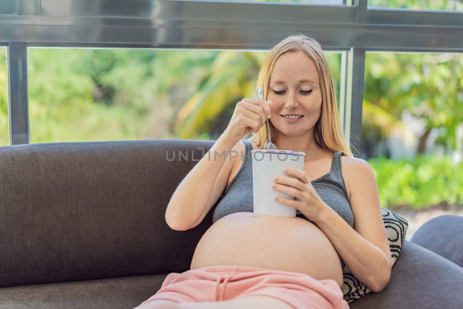 Happy pregnant young woman eating ice cream.