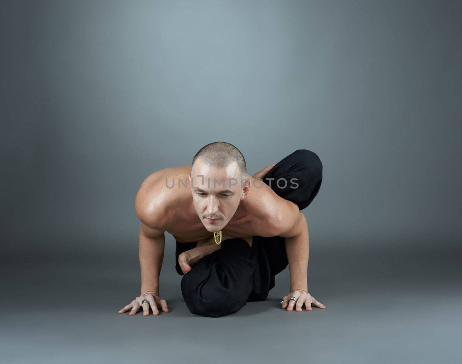 Yogi performs asana. Studio photo, on gray background