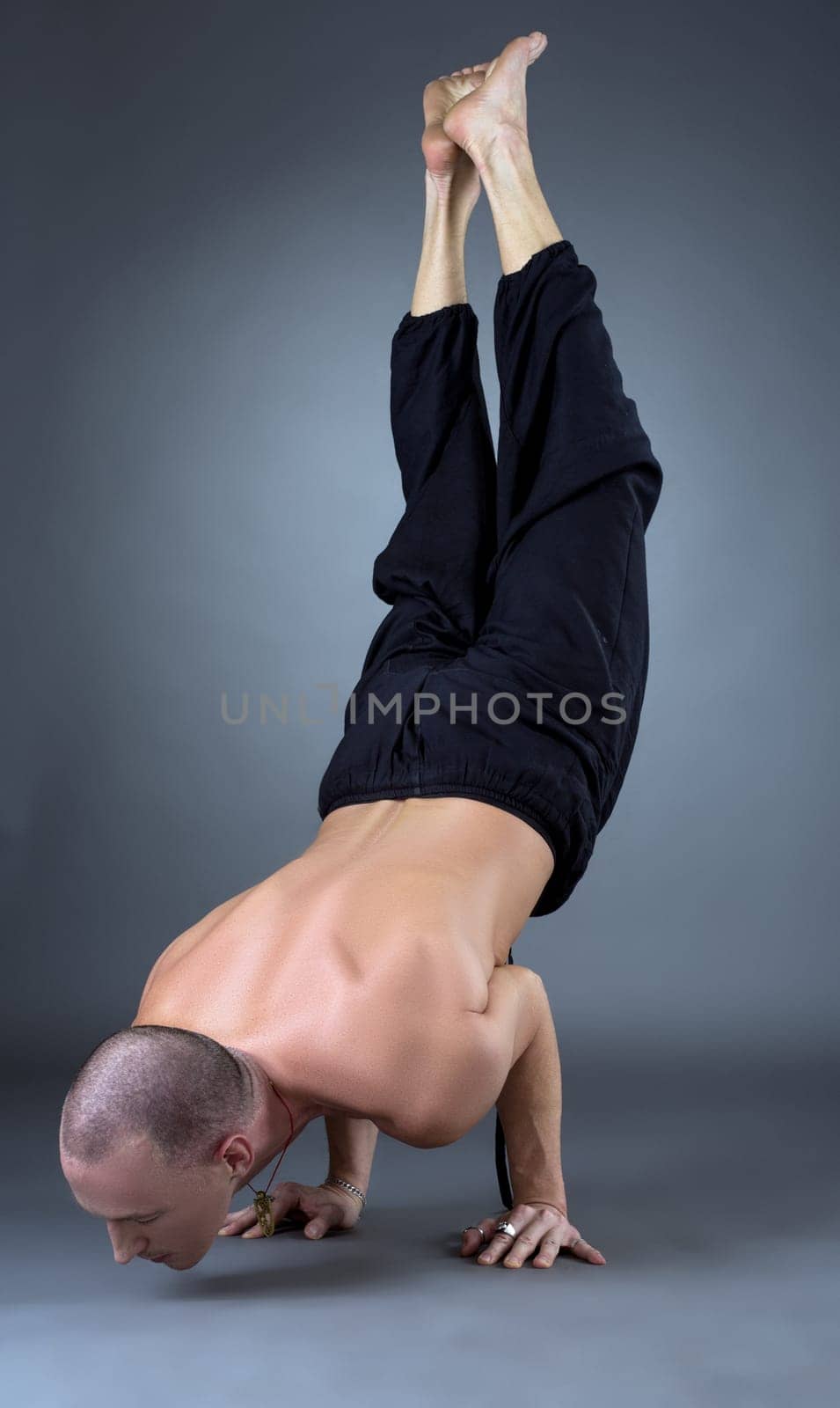 Image of yogi doing handstand in studio, on grey background