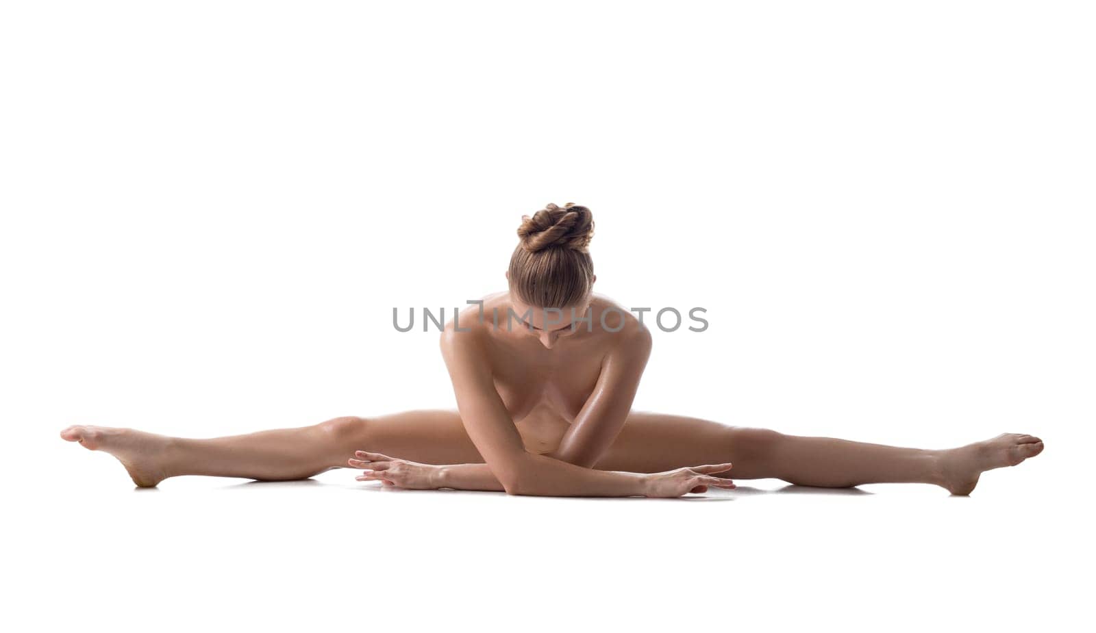 Nude female athlete doing gymnastic split, isolated on white