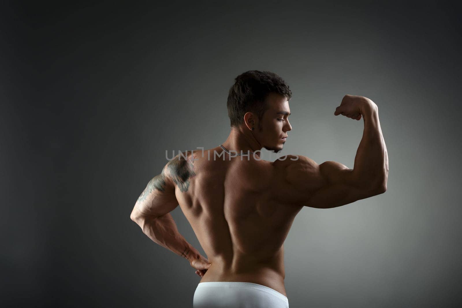 Back view of tattooed bodybuilder showing his biceps