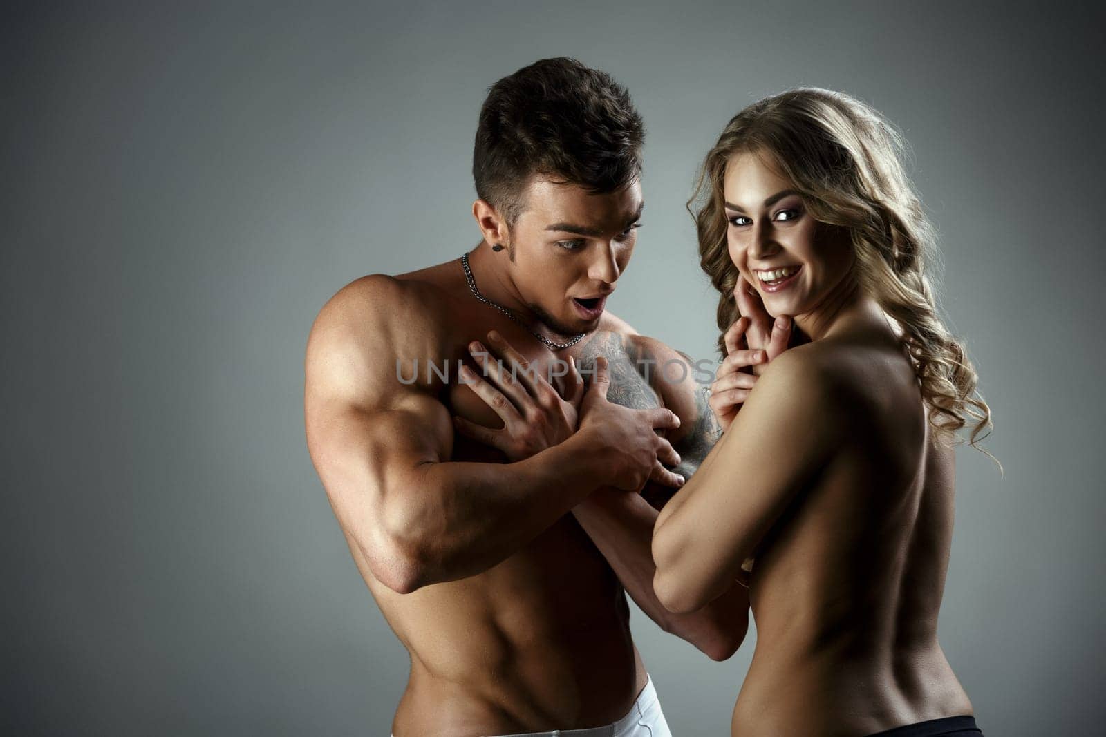 Studio image of man admires woman's body and she laughs