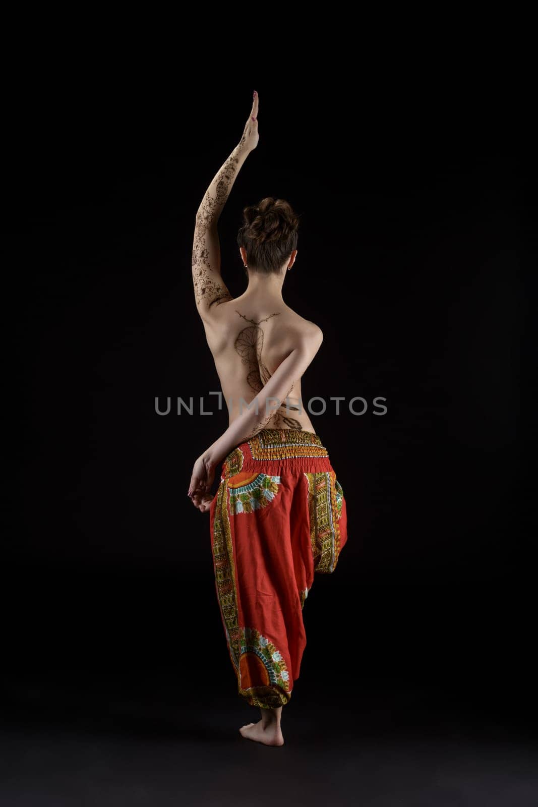 Yoga. Studio photo of topless woman doing asana, back to camera