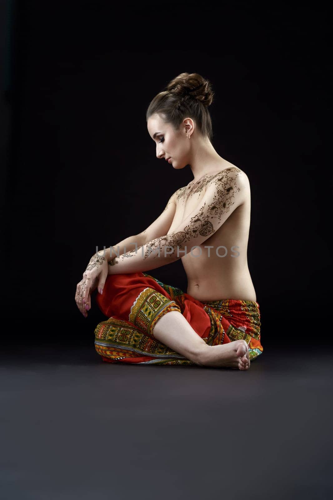 Studio photo of topless woman with henna patterns on body