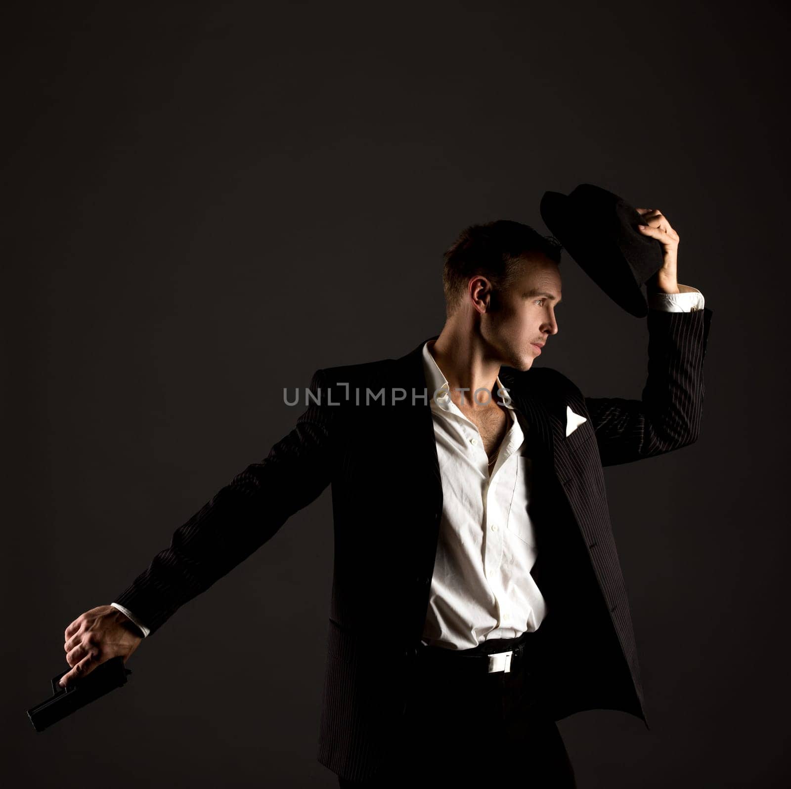 Handsome male dancer posing in gangster suit with gun