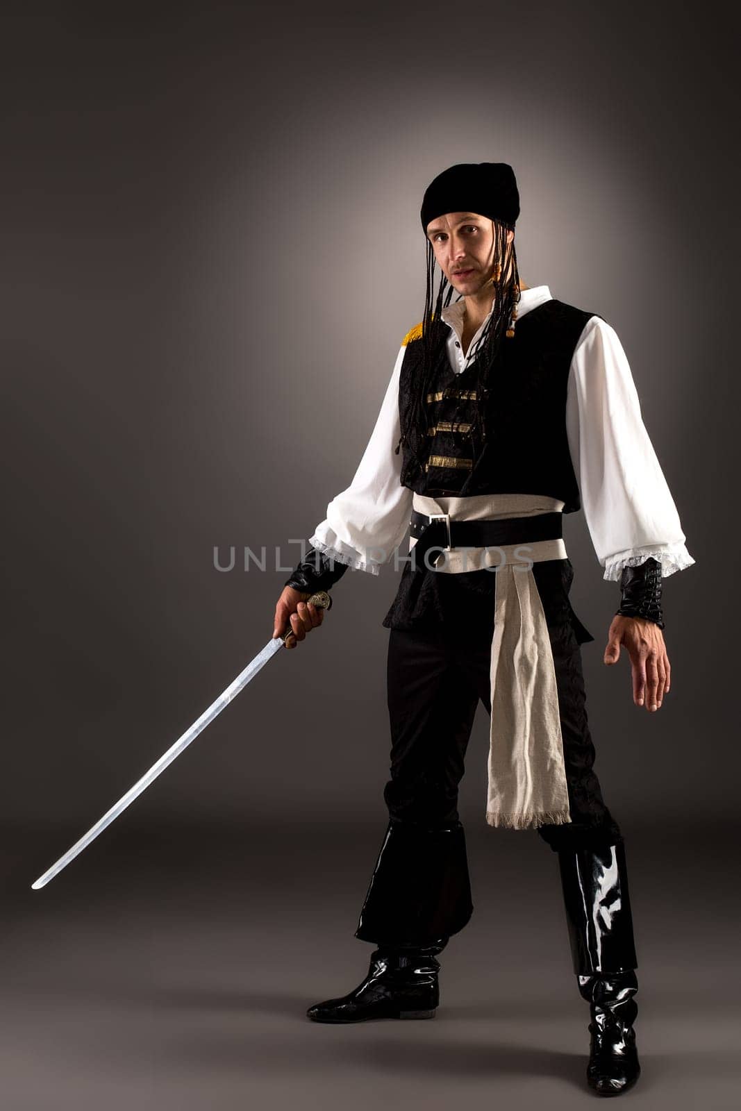 Attractive man dressed pirate for Halloween. Studio photo, on gray background