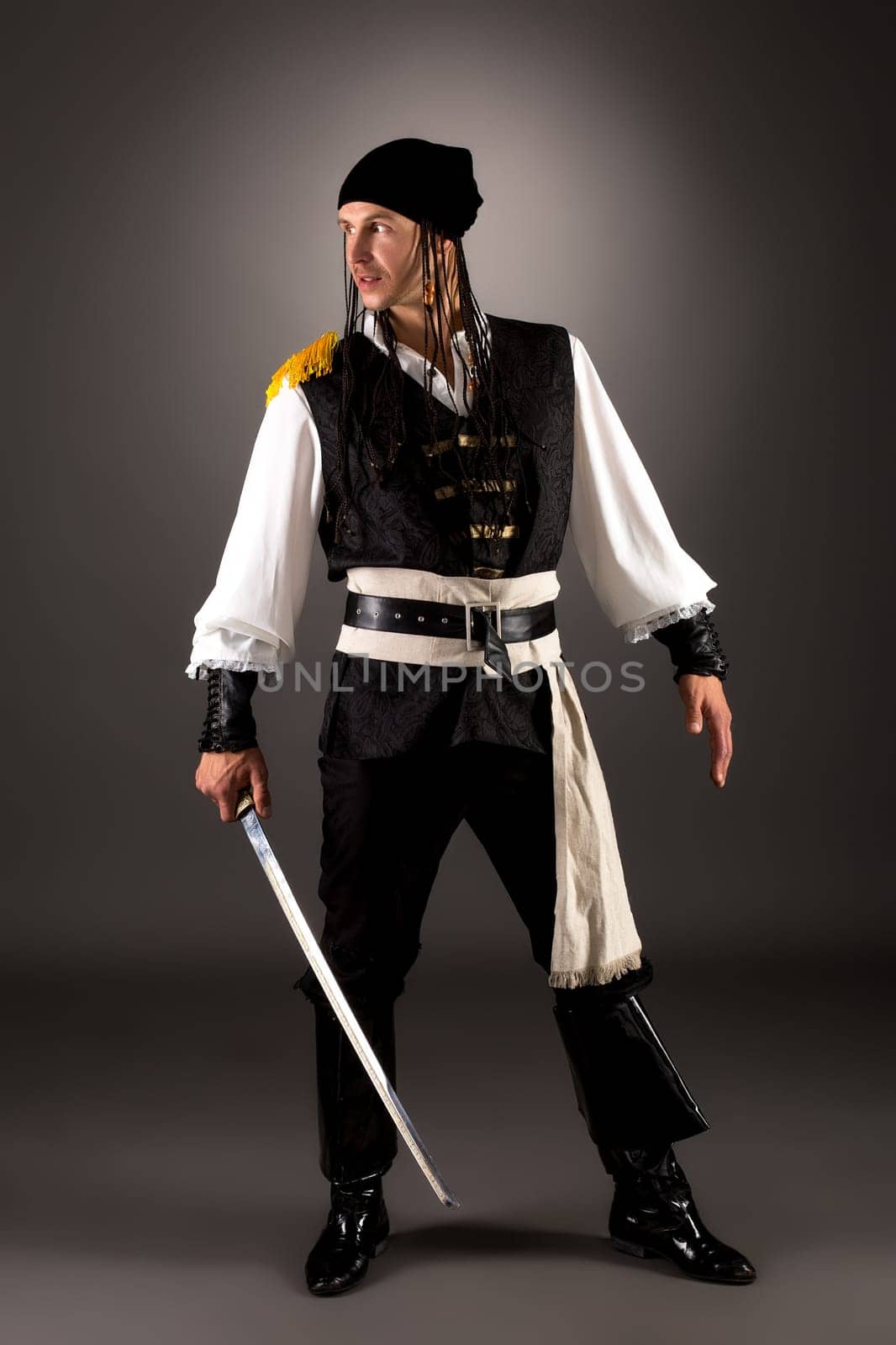 Daring pirate with saber. Studio photo on gray background
