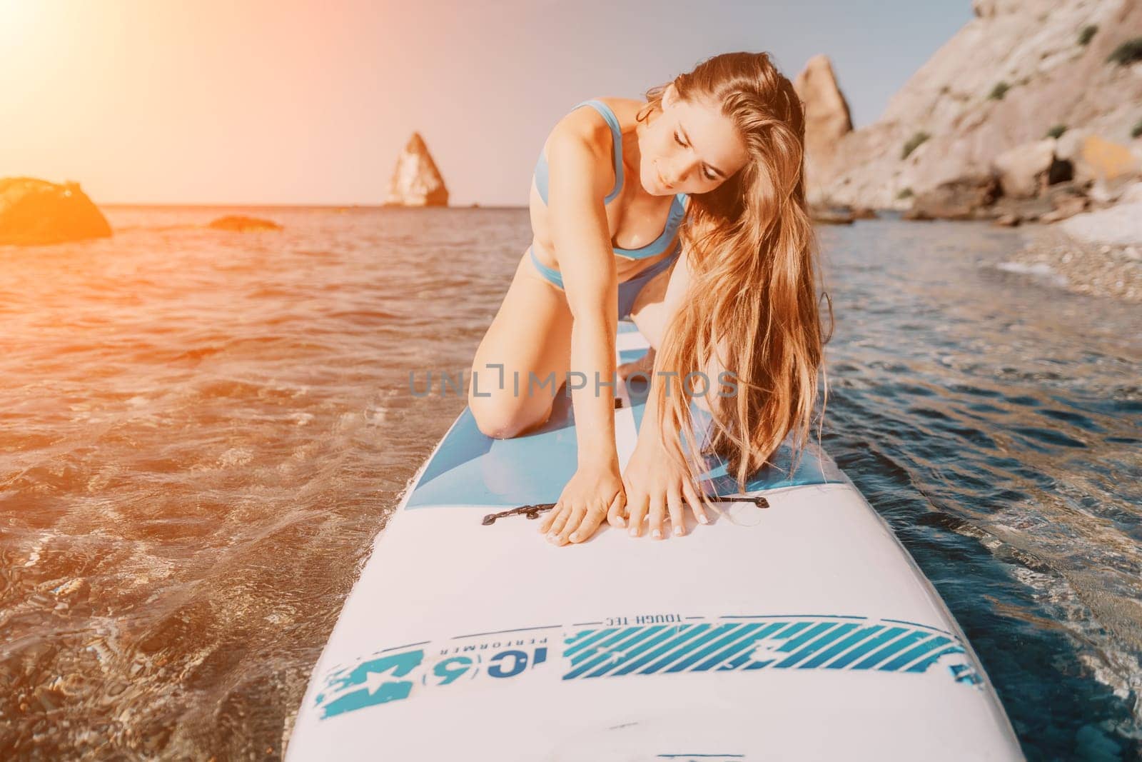 Close up shot of happy young caucasian woman looking at camera and smiling. Cute woman portrait in bikini posing on a volcanic rock high above the sea