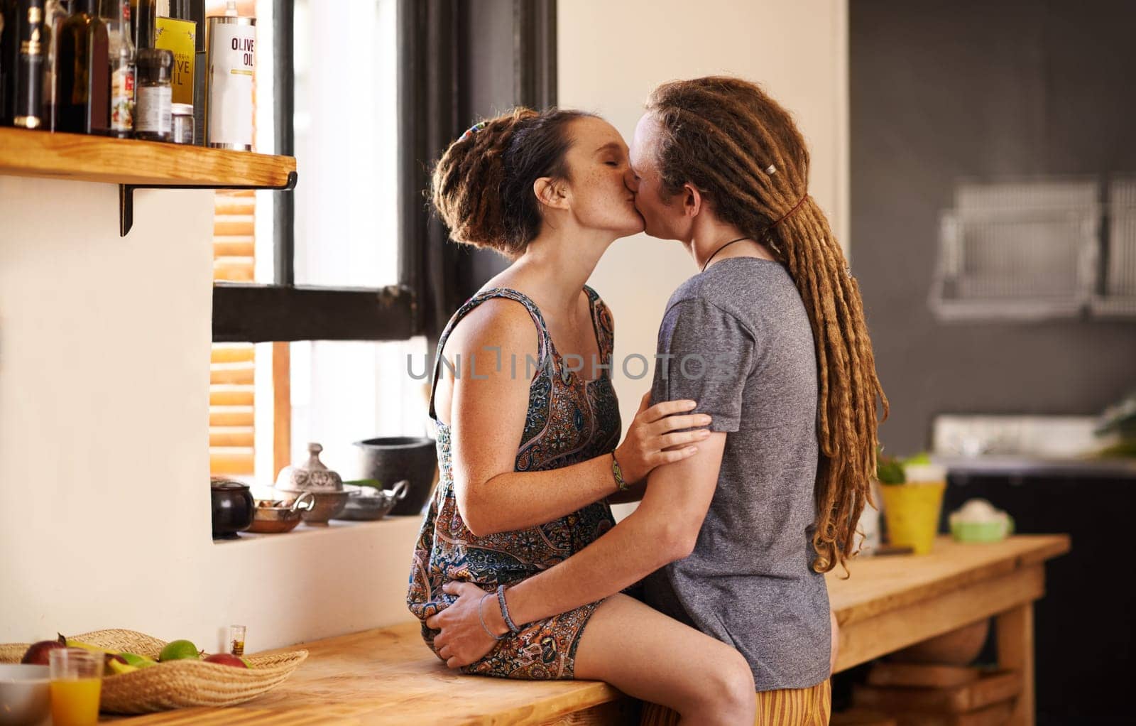 Kitchen, couple and kiss for love or care with romance for relationship, affection and connection for dating anniversary. Rasta, man and woman in home together for bonding, security and commitment. by YuriArcurs