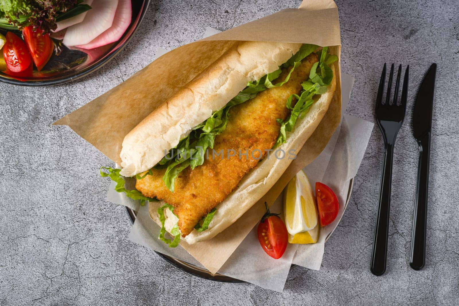 Fried fish sandwich with greens on the stone table. Turkish name Balik Ekmek by Sonat