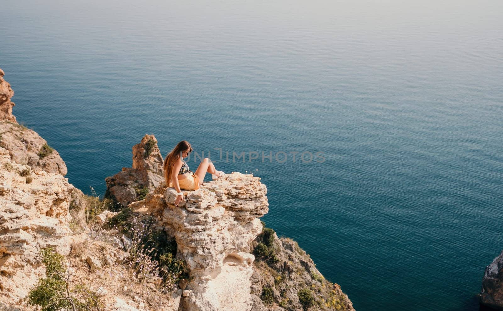 Woman travel sea. Happy tourist taking picture outdoors for memories. Woman traveler looks at the edge of the cliff on the sea bay of mountains, sharing travel adventure journey.