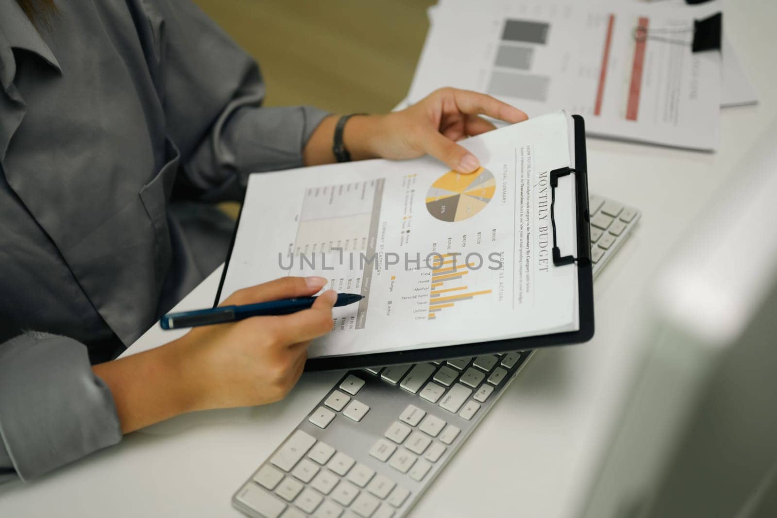 Unrecognizable female investor analyzing a documents with charts and graphs at her workplace.