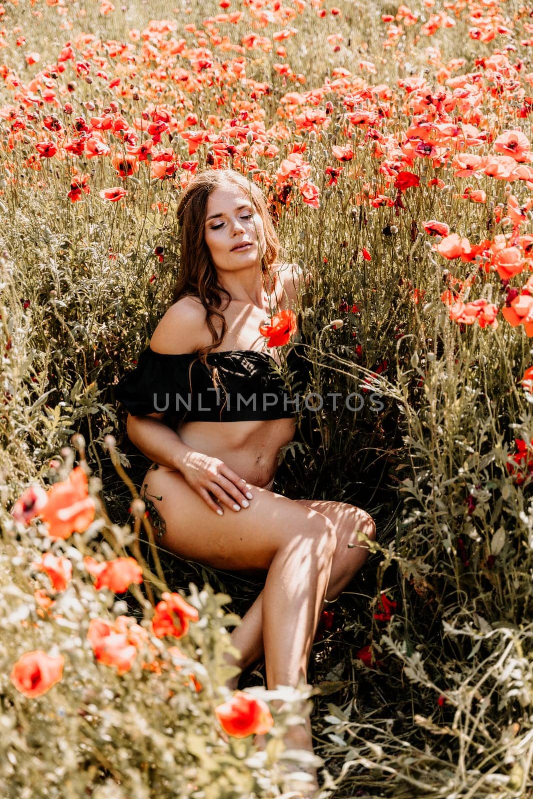 Woman poppies field. portrait of a happy woman with long hair in a poppy field and enjoying the beauty of nature in a warm summer day